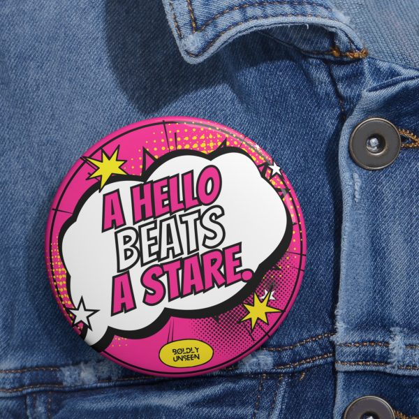 A Hello Beats a Stare. pin badge in hot pink with a white speech bubble, pinned on a denim jacket