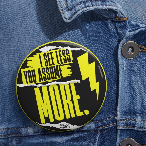 I See Less. You Assume More. pin badge pinned on a blue denim jacket